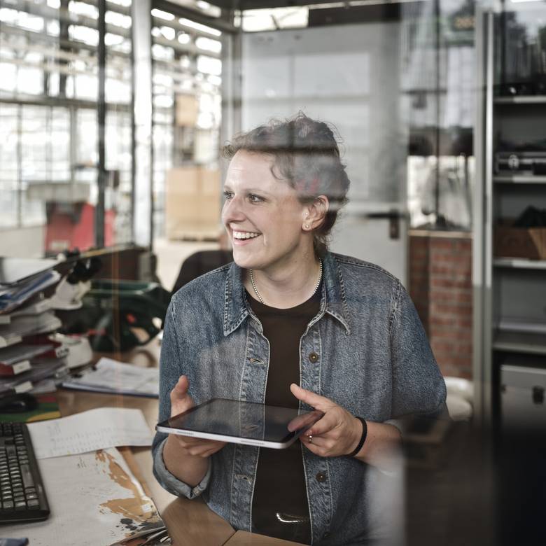 Unternehmerin steht am Schreibtisch mit Tablet in der Hand